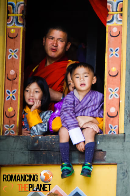 A father watching the Thimphu Domchoe along with his kids