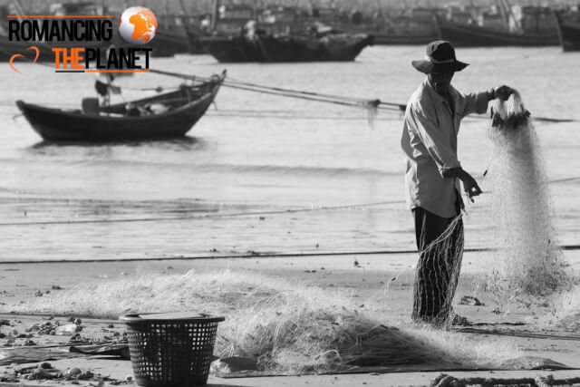Fisherman collecting oysters from his fishing nets in Mui Ne, Vietnam