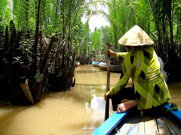 Vietnamese boatwoman, small river with palm trees, Mekong Delta