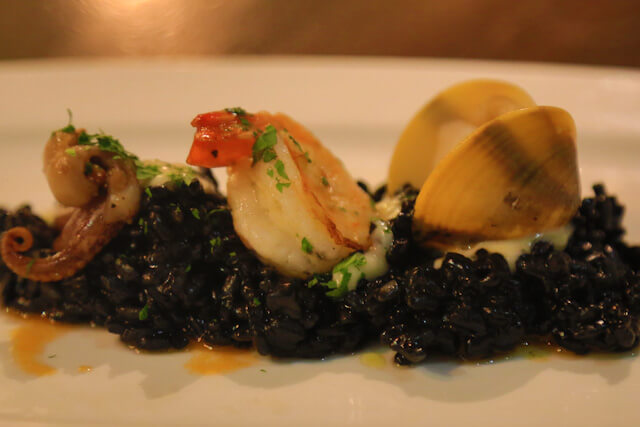 Rice cooked in Squid Ink accompanied with scallop, octopus arm and clam